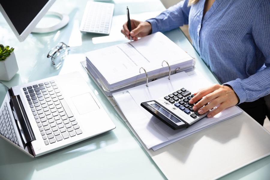 Professional tax preparer sitting at a desk with a laptop computer and a calculator